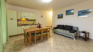 A compact living space with a dining area, kitchenette, and a sofa. - Villetta Seaside Sardegna (Villaputzu)