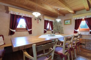 Ein Holzespeisetisch mit Stühlen, eine Steinwand und ein Gemälde an der Wand.