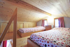Eine Hütte mit zwei Holzbettgestellen, einer Holztreppe und einem Fenster mit Vorhängen.