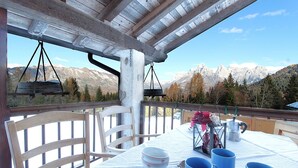A table set for dining with a mountain view, wooden chairs, and a hanging light fixture.