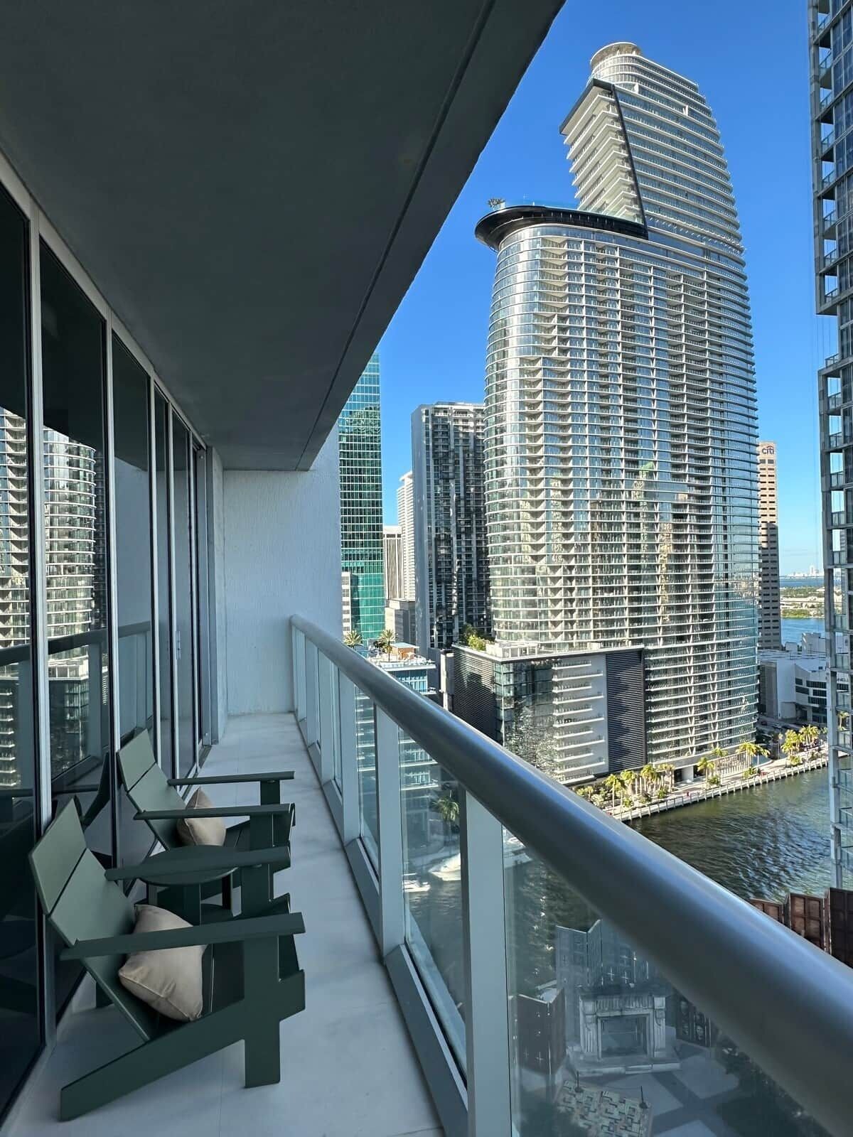 A balcony with a view of high-rise buildings and a body of water.