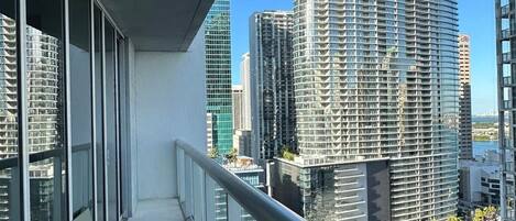 A balcony with a view of high-rise buildings and a body of water.
