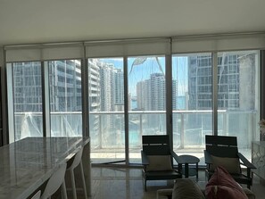 A balcony with a view of high-rise buildings, a dining table, and two chairs.