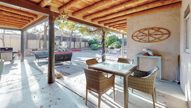 An outdoor patio with a wooden ceiling, wicker furniture, and a decorative wall piece. - Bright 3bd/2.5b Home w/Garage, Dog, Firepit (Albuquerque)
