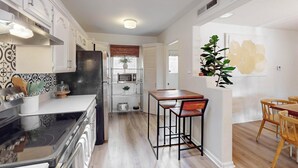 A modern kitchen with white cabinetry, a black refrigerator, and a wooden dining table with bar stools. - Bright 3bd/2.5b Home w/Garage, Dog, Firepit (Albuquerque)