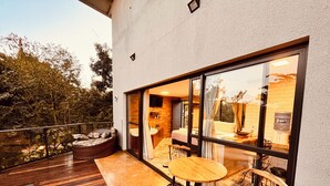 A modern outdoor patio with a wooden deck, a round table, and a seating area. - Nativos de Minas (Santana do Riacho)