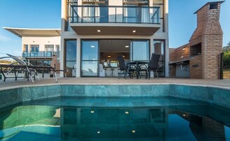 Un edificio moderno de dos pisos con una piscina al frente.