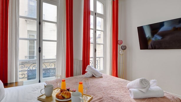 A hotel room with a bed, breakfast tray, and a TV on the wall.