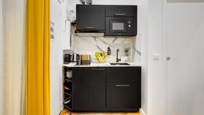 Een compacte keuken met zwarte kastjes, een ingebouwde magnetron en een marmeren achterwand.