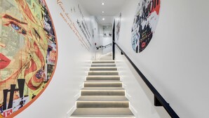 Een moderne trap met een leuning, omringd door muren versierd met verschillende posters en kunstwerken.