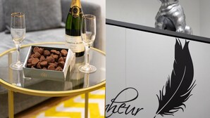 Een tafel met een champagnefles, twee glazen en een doos chocolade.