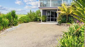 Et moderne hus med to etager, grusvej og frodig beplantning.