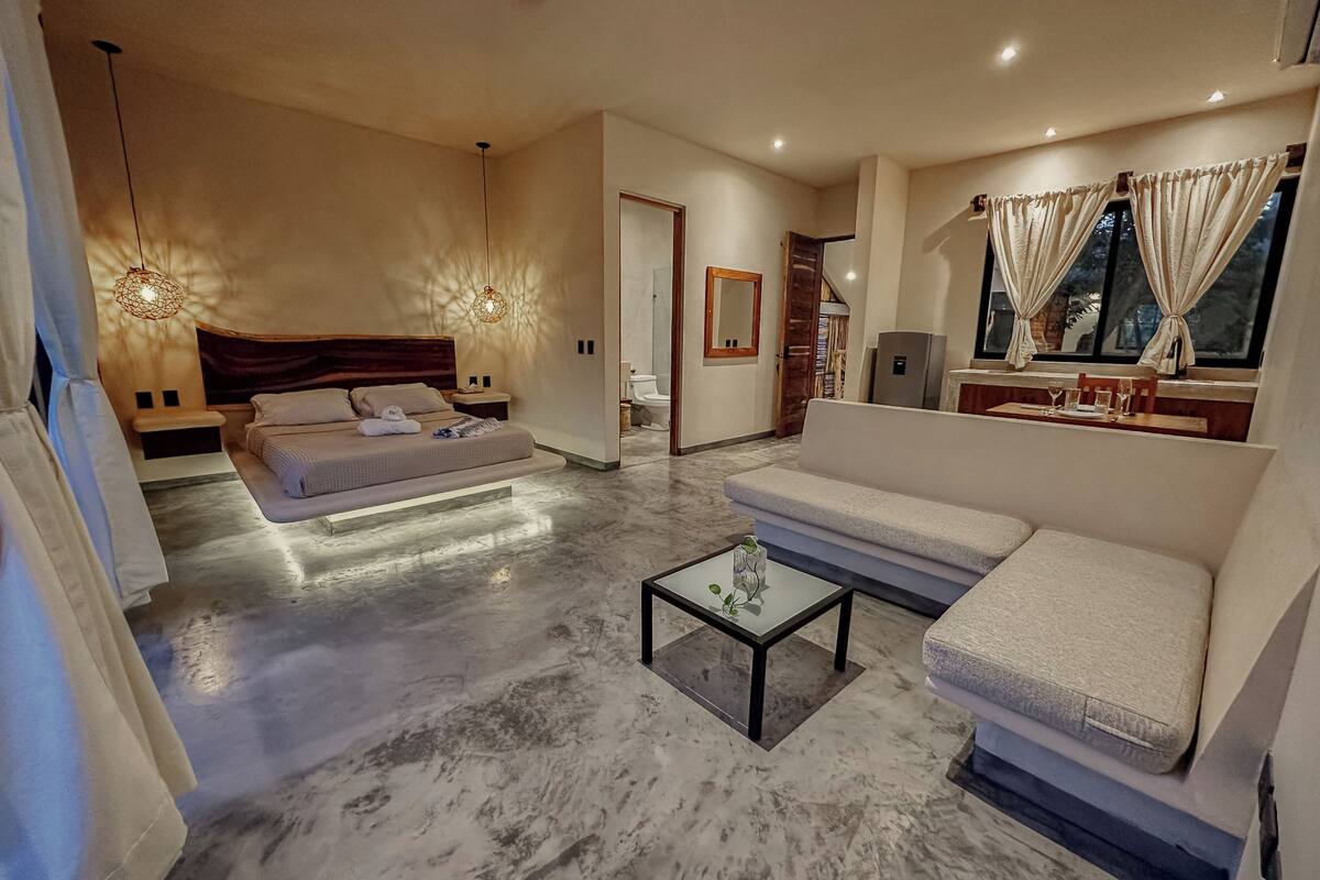A modern hotel room with a bed, sofa, and a small coffee table.