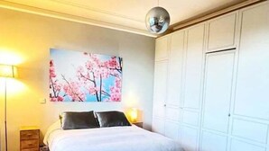 Une chambre à coucher avec un lit, une lampe fixée au mur, un tableau et une armoire.