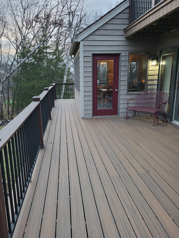 A wooden deck with a red door and a bench.