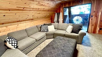 A cozy room with a sectional sofa, a ceiling fan, and a large window.