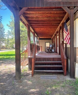 A wooden porch with a metal grate, an American flag, and a door.