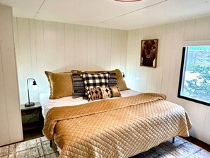 Una camera da letto con un letto, cuscini, un comodino, una lampada e una finestra vista.
