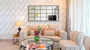 A living room with a sofa, armchair, glass coffee table, magazine, lamp, vase, and a mirror on the wall. - 2 Bedroom With Private Terrace and Communal Pool in Marbella Center Ricardo Soriano Terrace (Marbella)