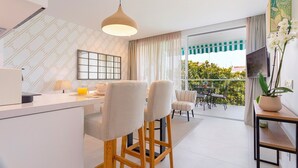A modern kitchen with a dining area, a balcony with a view, and a mounted TV. - 2 Bedroom With Private Terrace and Communal Pool in Marbella Center Ricardo Soriano Terrace (Marbella)