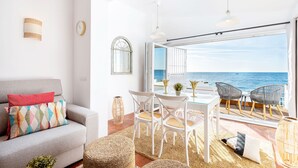 Una sala de estar moderna con sofá, sillas, una mesa y vista al mar.