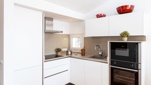 Una cocina moderna con armarios blancos, electrodomésticos de acero inoxidable y un tazón rojo sobre la encimera.