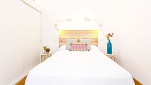Un dormitorio con cama, mesitas de noche, cabecera y pared con diseño geométrico.