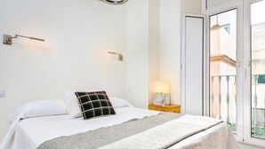 A bedroom with a bed, a nightstand, a lamp, and a view of the outside balcony. - Amazing Duplex up to 4 Guest Private Terrace Real de La Carreteria (Seville)