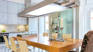 A modern kitchen with a wooden dining table, chairs, and a built-in oven. - Amazing Duplex up to 4 Guest Private Terrace Real de La Carreteria (Seville)