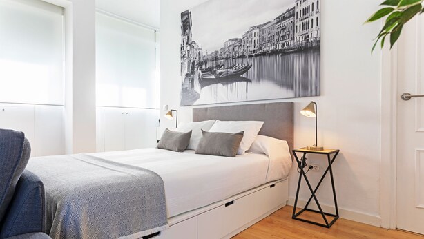 Ein Schlafzimmer mit einem Bett, Nachttischen, einem Sessel und einem Wandbild.