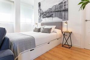 A bedroom with a bed, bedside tables, a chair, and a wall-mounted artwork. - Amazing Penthouse in Triana With Unique City Views Castilla Terrace (Seville)