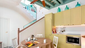 A kitchen with a dining table, chairs, a microwave, and a staircase with a view to an upper floor. - Beautiful 4 Bd House With Terrace Views to the Alcazar Gardens Casa Alcazar (Seville)