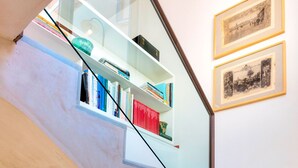 A staircase with a glass railing, a bookshelf, and two framed pictures on the wall. - Beautiful 4 Bd House With Terrace Views to the Alcazar Gardens Casa Alcazar (Seville)