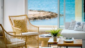 Una habitación con mobiliario de mimbre, un sofá blanco y vistas al mar.