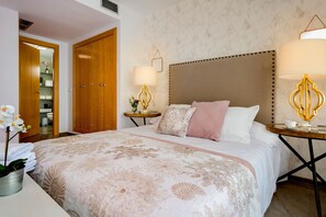 Ein Hotelzimmer mit einem großen Bett, zwei Nachttischen mit Lampen, einem Holzschrank und einem durch eine geöffnete Tür einsehbaren Badezimmer.