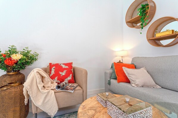 A living room with a sofa, armchair, round coffee table, and wall-mounted shelves.