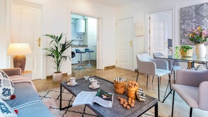 A modern living room with a sofa, coffee table, chairs, a lamp, a potted plant, and a dining area with a table and chairs. - Cozy Bright Apartment in the Center of Granada Reyes Cat Licos (Granada)