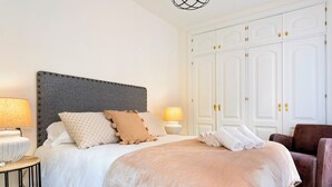 A hotel room with a bed, two bedside lamps, a wardrobe, and a chair. - Cozy Bright Apartment in the Center of Granada Reyes Cat Licos (Granada)