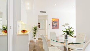 Un comedor moderno con una mesa de vidrio, sillas blancas y plantas en macetas.