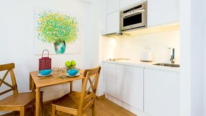 Une cuisine moderne avec des meubles blancs, un four en acier inoxydable et une table à manger avec des chaises.