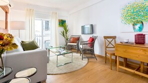 Un salon moderne avec un canapé, une table basse, des fauteuils, un téléviseur et un tableau.