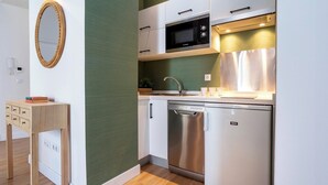 A compact kitchen with white cabinets, a Bosch microwave, a dishwasher, and a wooden side table with a mirror. - Cozy 2 Bedrooms Apartment in the City Center Zaragoza I (Seville)