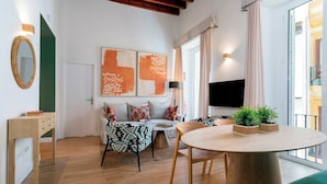 A modern living room with a round wooden table, a sofa with patterned cushions, a TV, and artwork on the wall. - Cozy 2 Bedrooms Apartment in the City Center Zaragoza I (Seville)