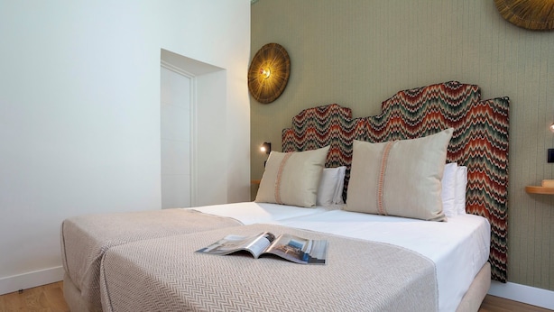 A neatly made bed with a patterned bedspread and pillows, a magazine on the bed, and a decorative wall hanging above the bed. - Cozy 2 Bedrooms Apartment in the City Center Zaragoza I (Seville)