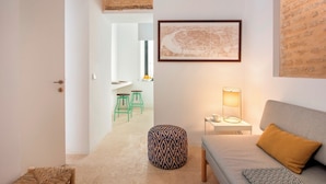 A modern living room with a grey sofa, a patterned ottoman, a floor lamp, and a framed map on the wall. - Cozy Studio in Santa Cruz Quarter Santa Teresa I (Seville)