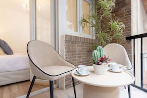 A room with a white sofa, two chairs, a table with a cup and saucer, and a potted plant. - Cozy Apartment Near City Center Lope de Vega (Granada)