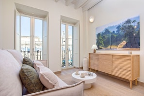 A modern living room with a sofa, a coffee table, a wooden cabinet, and a large painting on the wall.