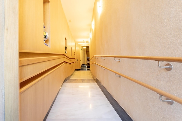 A corridor with wooden paneling, marble flooring, and a handrail.