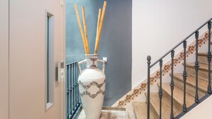 Una escalera con un jarrón blanco y ramas de bambú en el rellano.