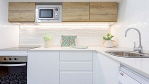 A modern kitchen with white cabinetry, a microwave, a sink, and a small oven. - Exclusive Apartament in Malaga Center Soho (Málaga)